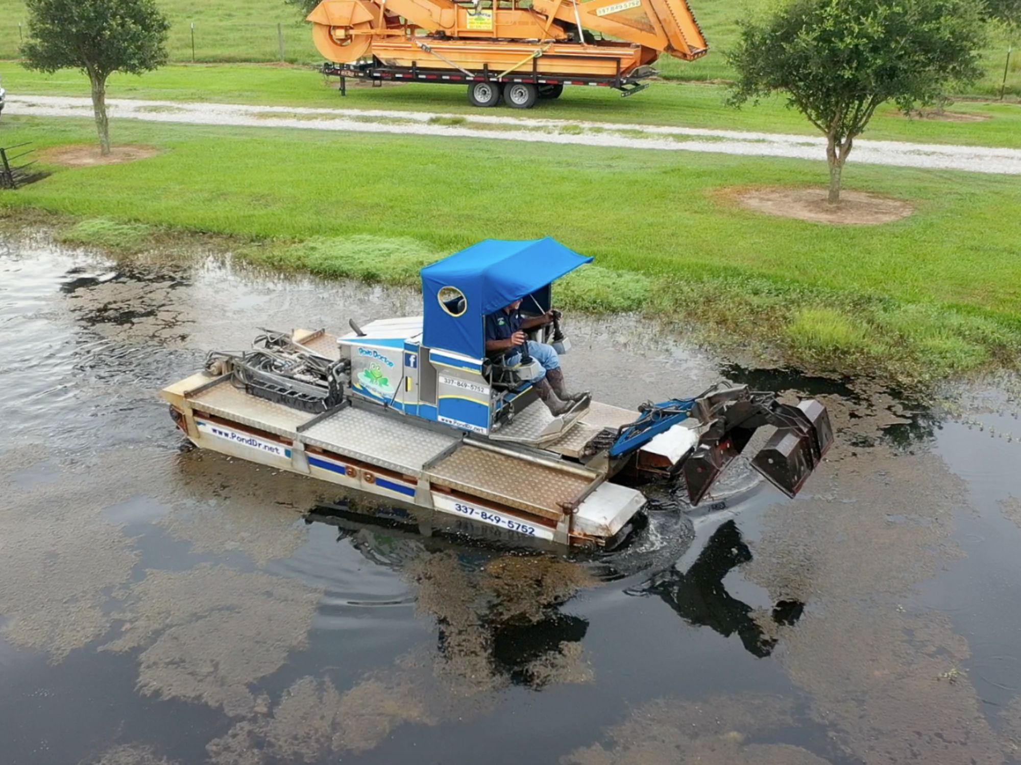 Truxor with claw attachment removing debris from pond